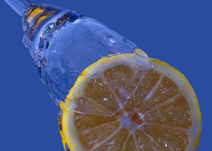 Water Splash on Lemon Slice Against Blue Background