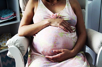 Pregnant woman holding belly in floral dress