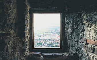 Old stone window frame overlooking a distant town