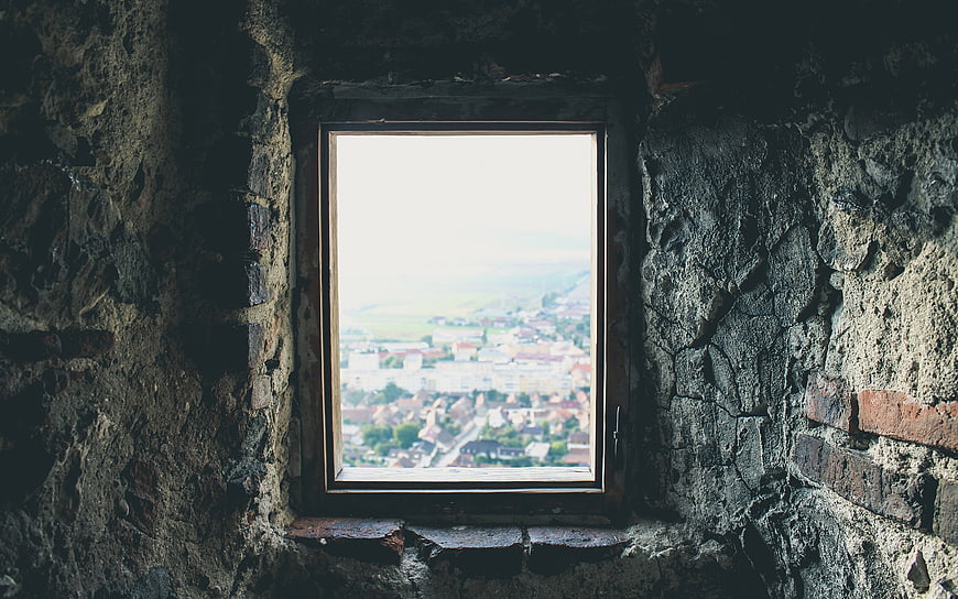 Old stone window frame overlooking a distant town