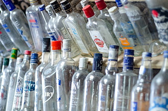 Rows of empty clear glass vodka bottles on wooden shelves