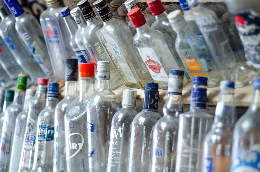 Rows of empty clear glass vodka bottles on wooden shelves