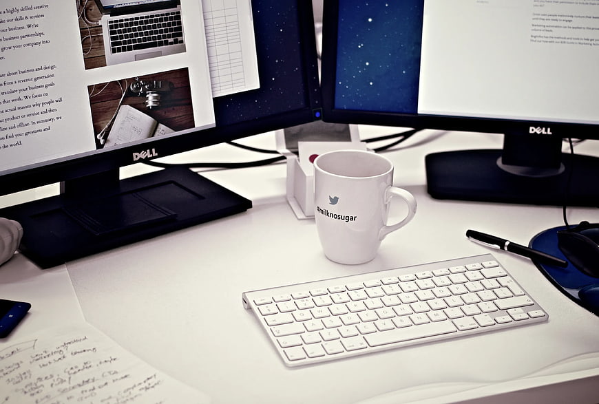 Modern office desk with dual monitors and branded coffee mug