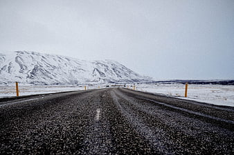 Wet asphalt road stretching through snowy winter landscape