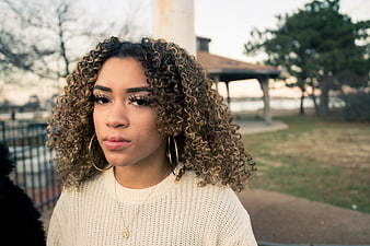 Portrait of young woman with curly hair in park