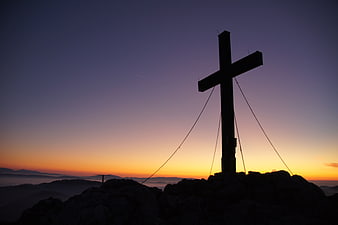 Silhouette of Summit Cross at Sunrise Over Mountain Peaks