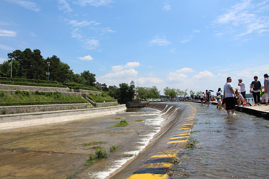 People wading in shallow river weir at Jingyuetan Park Changchun