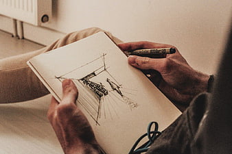 Man Sketching Perspective Drawing in Notebook