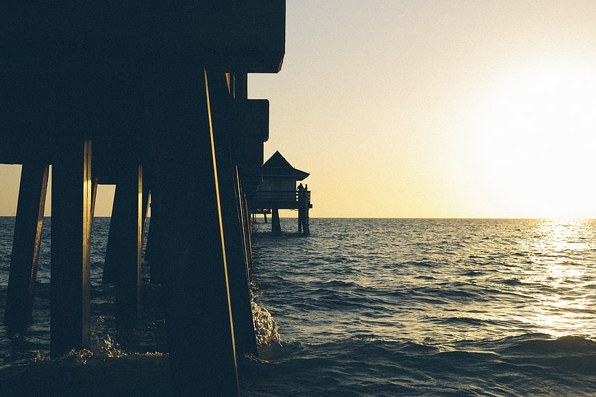 Silhouette of wooden pier over ocean at golden hour