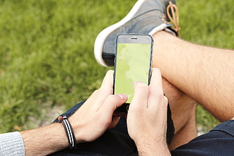 Man using smartphone with green screen on grass