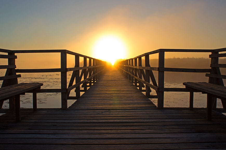 Sunrise over wooden pier on misty lake