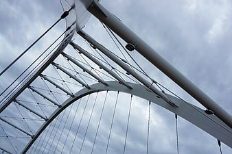 Low angle view of modern white steel arch bridge cables
