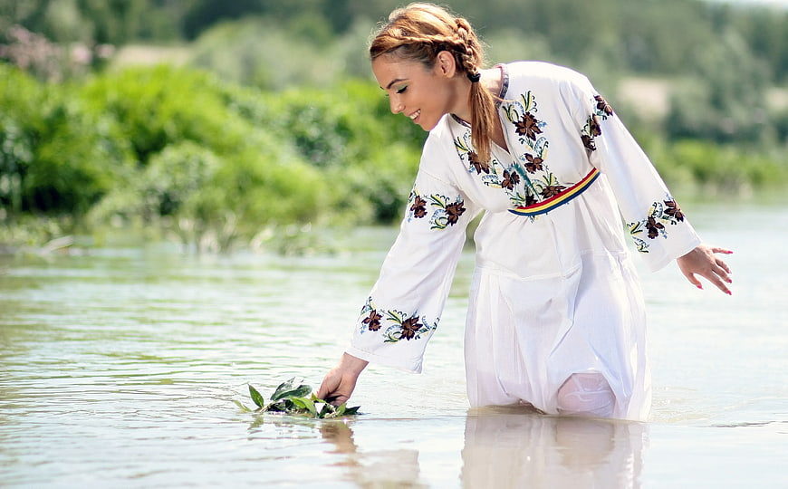 Woman in Traditional Embroidered Dress Floating Flowers in River