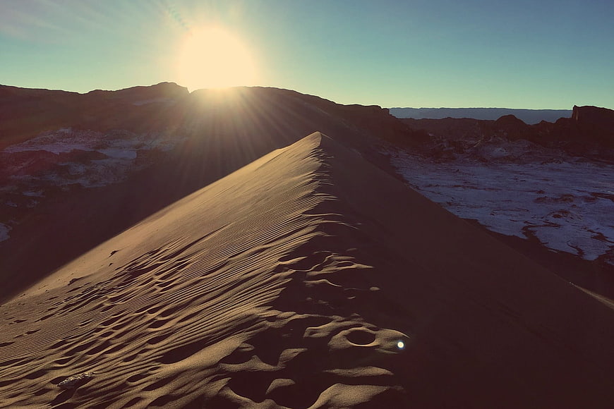 Sunset over sand dune with ripples and snow