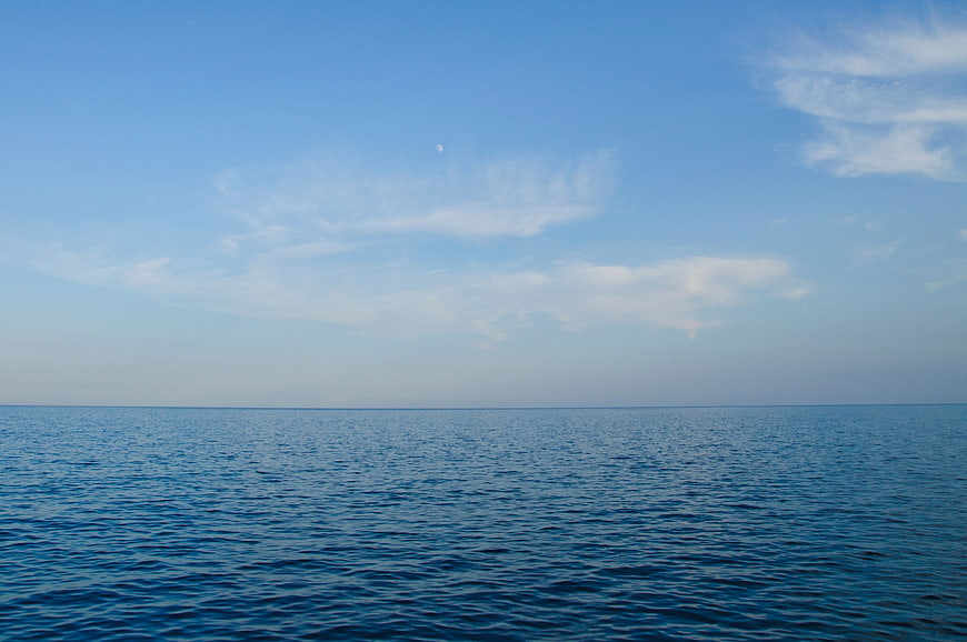 Calm Blue Ocean Horizon with Wispy Clouds and Moon