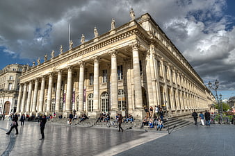 Grand neoclassical opera house with columns and dramatic sky
