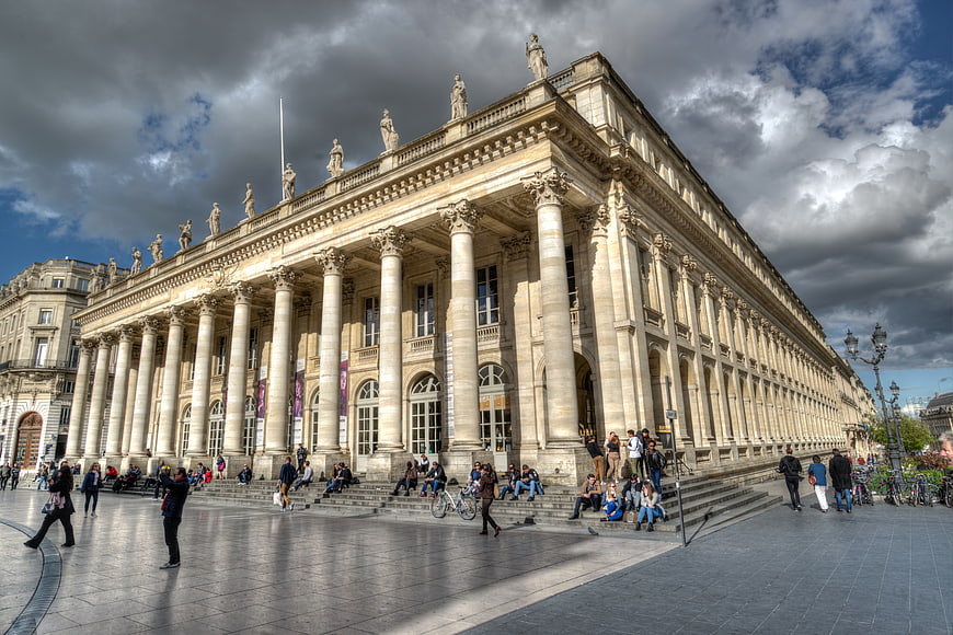 Grand neoclassical opera house with columns and dramatic sky