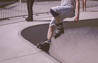 Roller skater performing trick in concrete skate park bowl