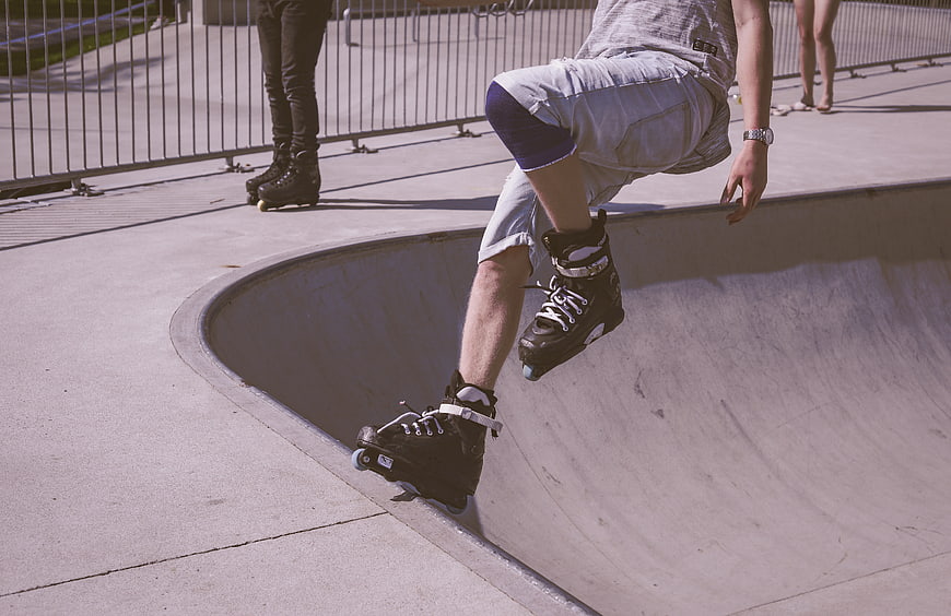 Roller skater performing trick in concrete skate park bowl
