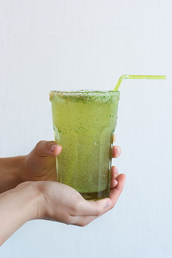 Hands holding green cucumber lemonade drink