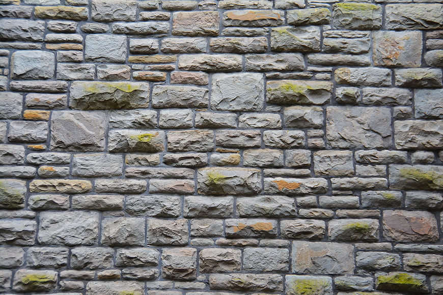 Textured Gray Stone Wall Background with Moss Accents