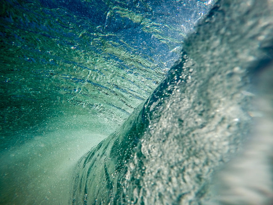 Underwater view of a crashing ocean wave with bubbles