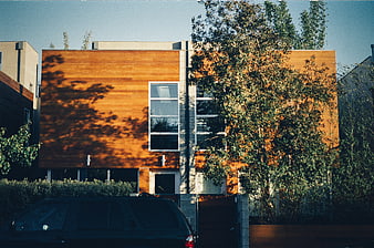 Modern wooden house with trees and car in foreground