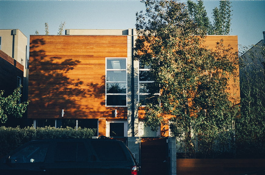 Modern wooden house with trees and car in foreground