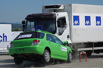 Green car crash test into white truck