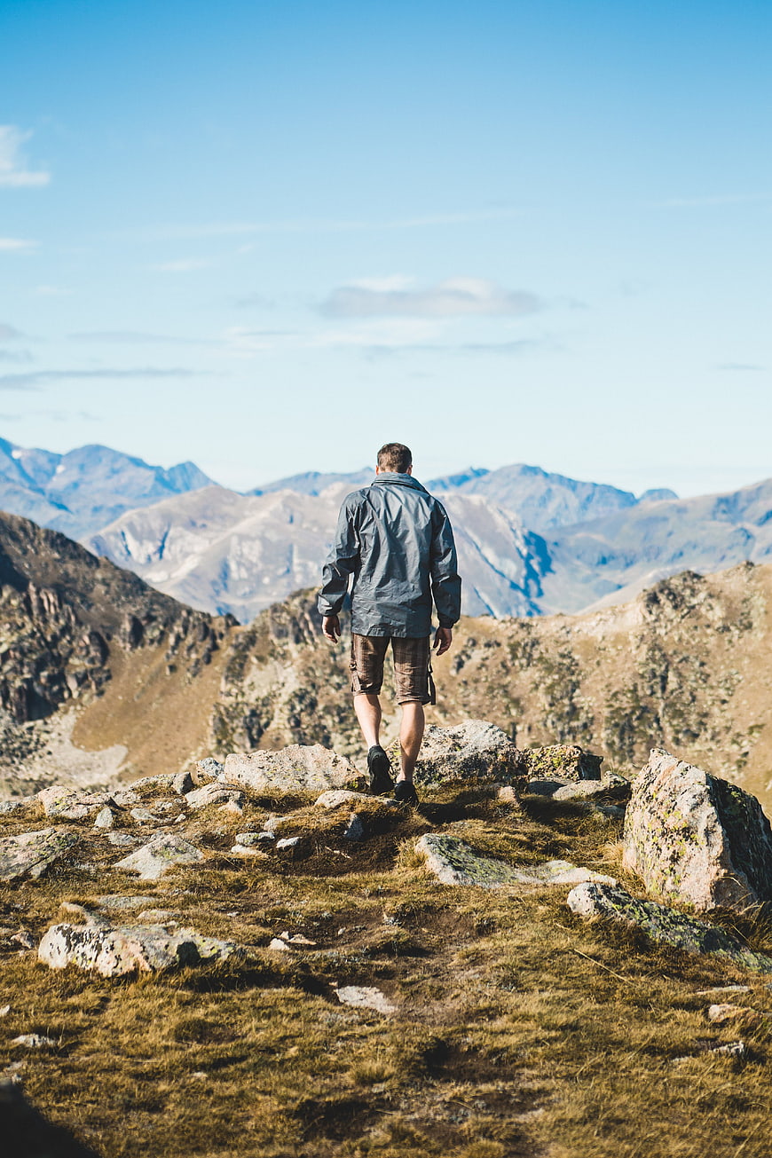 Hiker Walking on Rocky Mountain Ridge with Scenic View
