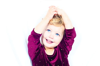 Happy little girl with blue eyes smiling against white background