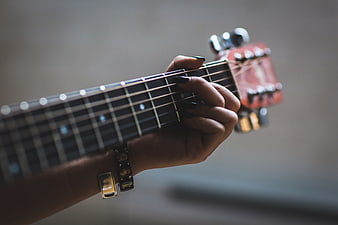 Close-up of woman playing ukulele with dark nail polish