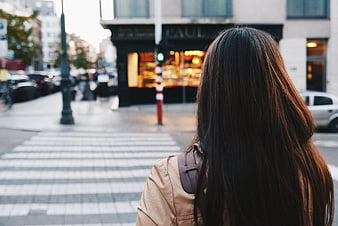 Woman with long hair standing on city street corner