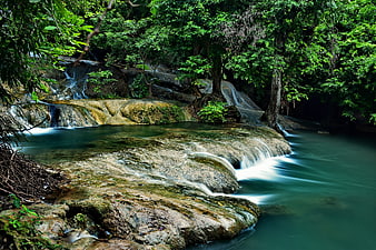 Serene tropical waterfall cascading over mossy rocks in lush forest