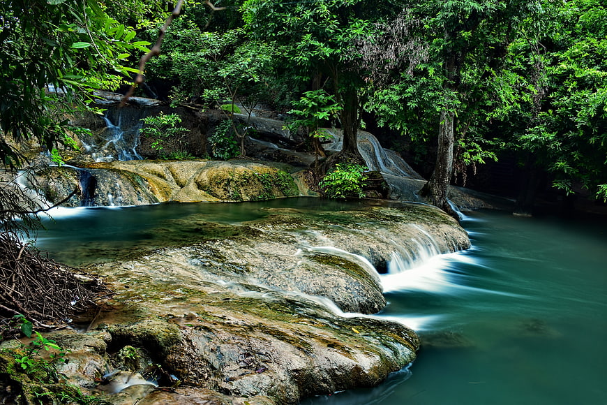 Serene tropical waterfall cascading over mossy rocks in lush forest