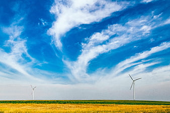 Wind turbines in a golden field under a dramatic blue sky