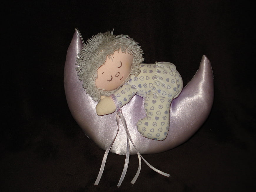 Sleeping baby doll on purple crescent moon plush toy