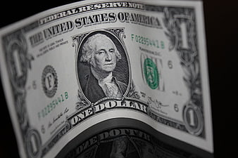 Close-up of a curved United States one dollar bill on a black background
