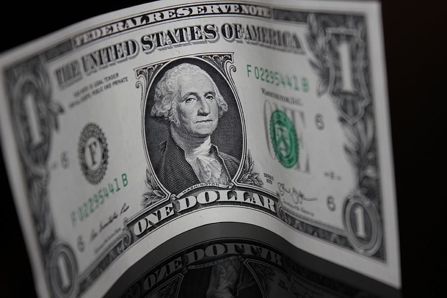 Close-up of a curved United States one dollar bill on a black background