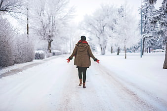Woman walking down snowy winter road with red gloves