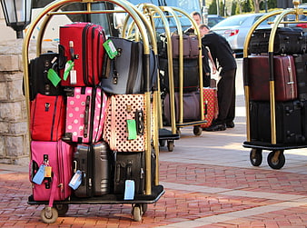 Colorful luggage on gold bellhop carts at hotel entrance