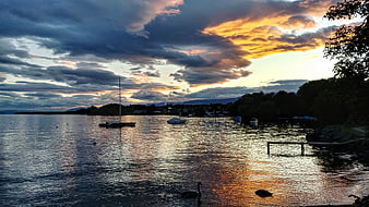Dramatic sunset over a lake with boats and swans