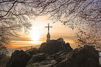Silhouette of Cross on Rocky Peak at Sunset