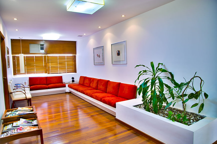 Modern waiting room with red sofas and wooden floor