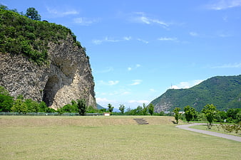 Grassy park with large cliff face and blue sky