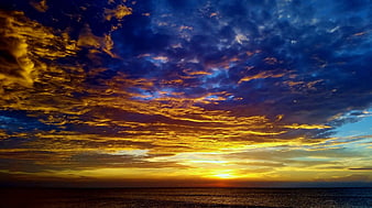 Dramatic sunset over ocean with golden clouds