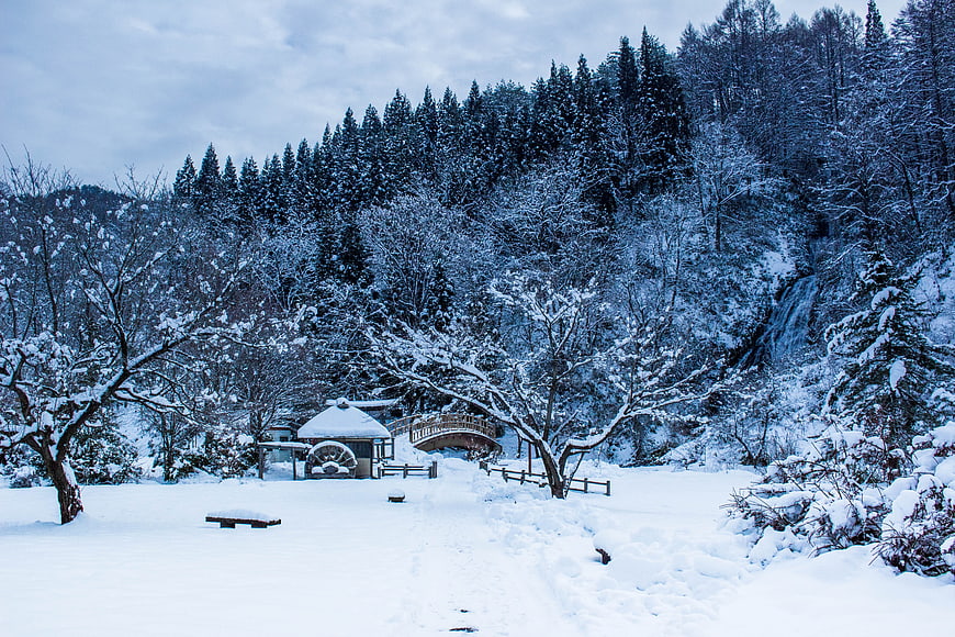 Snowy Japanese Landscape With Thatched Roof House And Arched Bridge