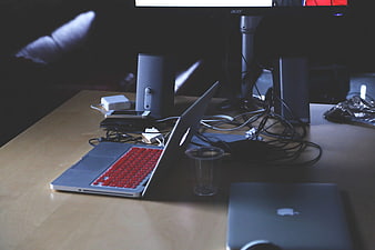Cluttered workspace with laptops, speakers, and tangled wires