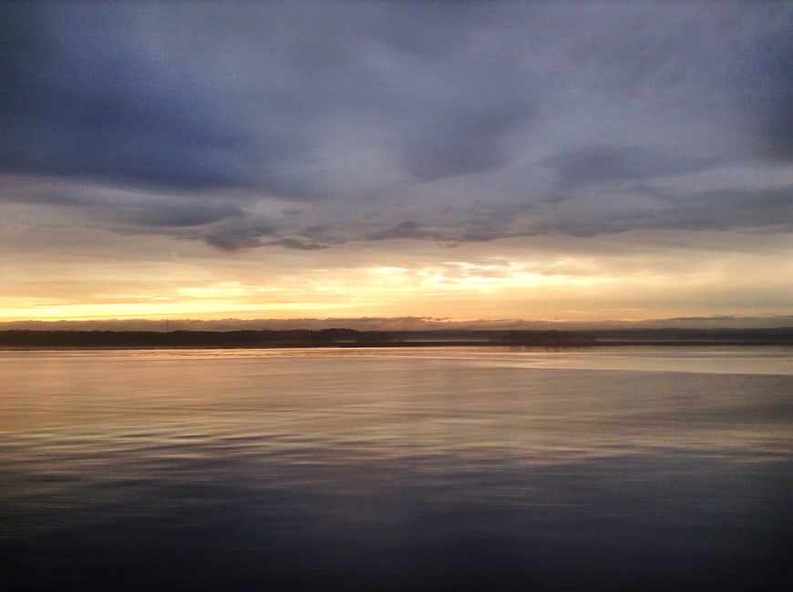 Serene Sunset Over Calm Water with Cloudy Sky
