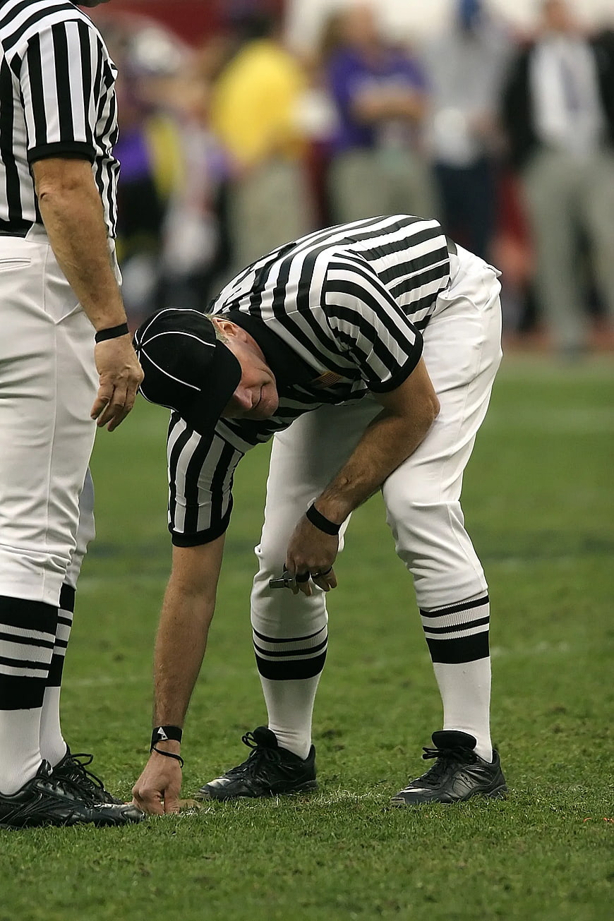 Football Referee Marking Grass with Chalk on Field